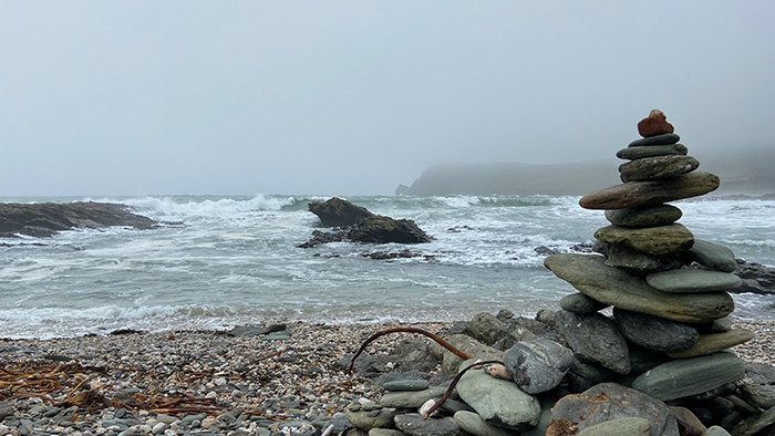 Rough seas and high winds in Devon and, in the foreground, a serenely balanced pile of stones